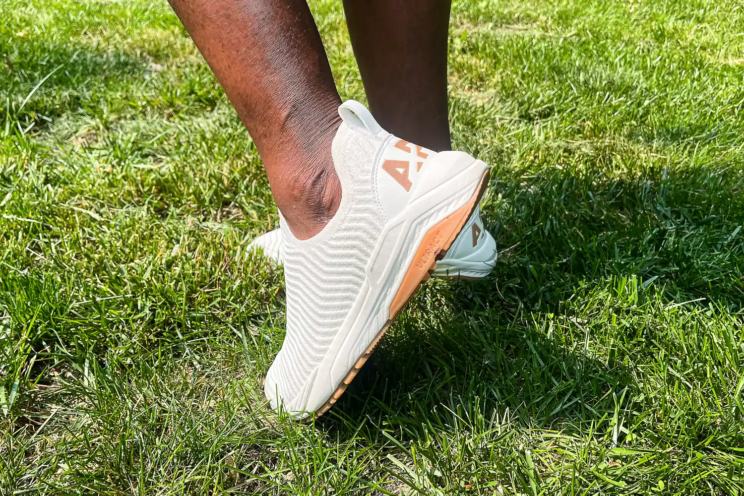A side view of a person wearing the APL Men's TechLoom Travelers while walking through grass