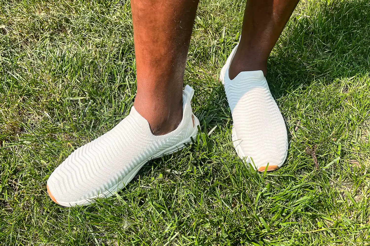A person wears the APL Men's TechLoom Travelers while standing in grass