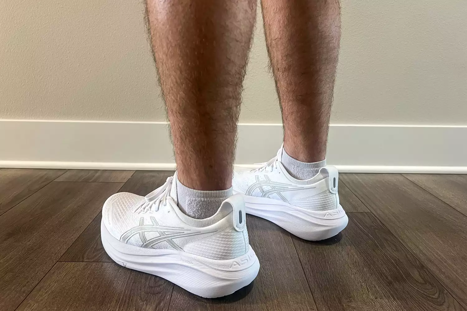 A close-up of a person's legs as they wear the Asics Men's GEL-NIMBUS 27 sneakers indoors