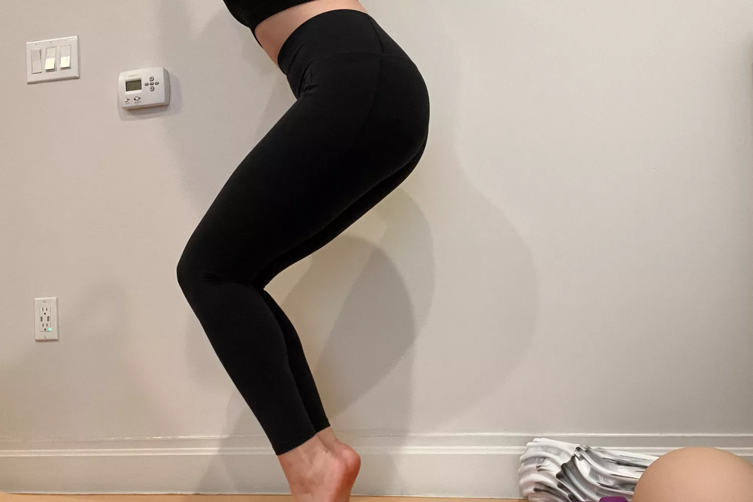 A person stands on their toes while wearing the Athleta Transcend Stash Tight