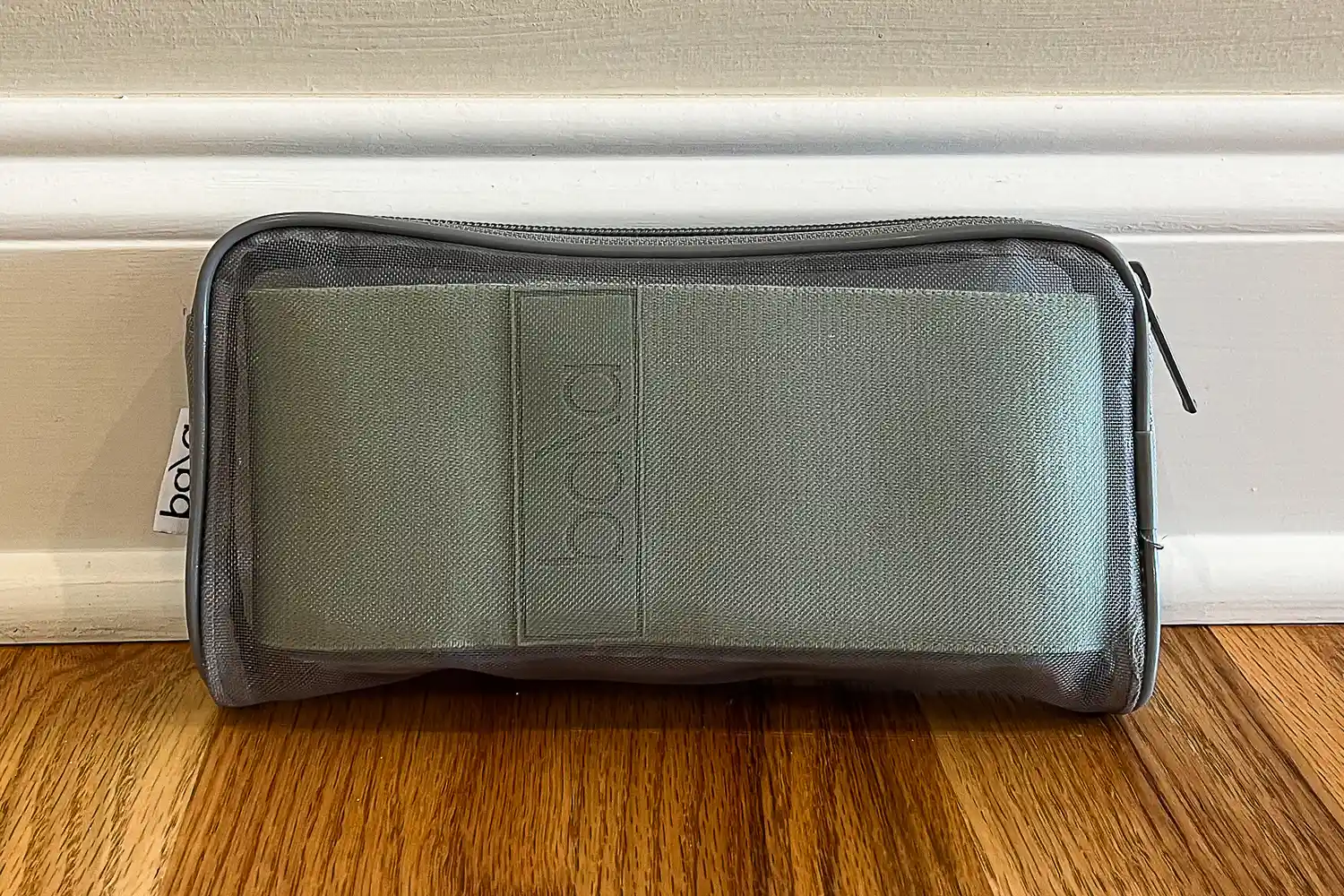 A zipper pouch with Bala Bands placed on a wooden floor near a wall trim