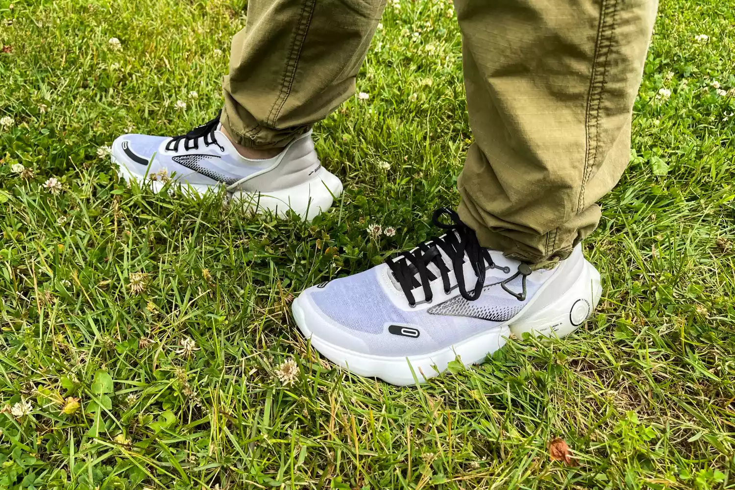 A close-up of a person's feet in grass while wearing Brooks Aurora BL sneakers