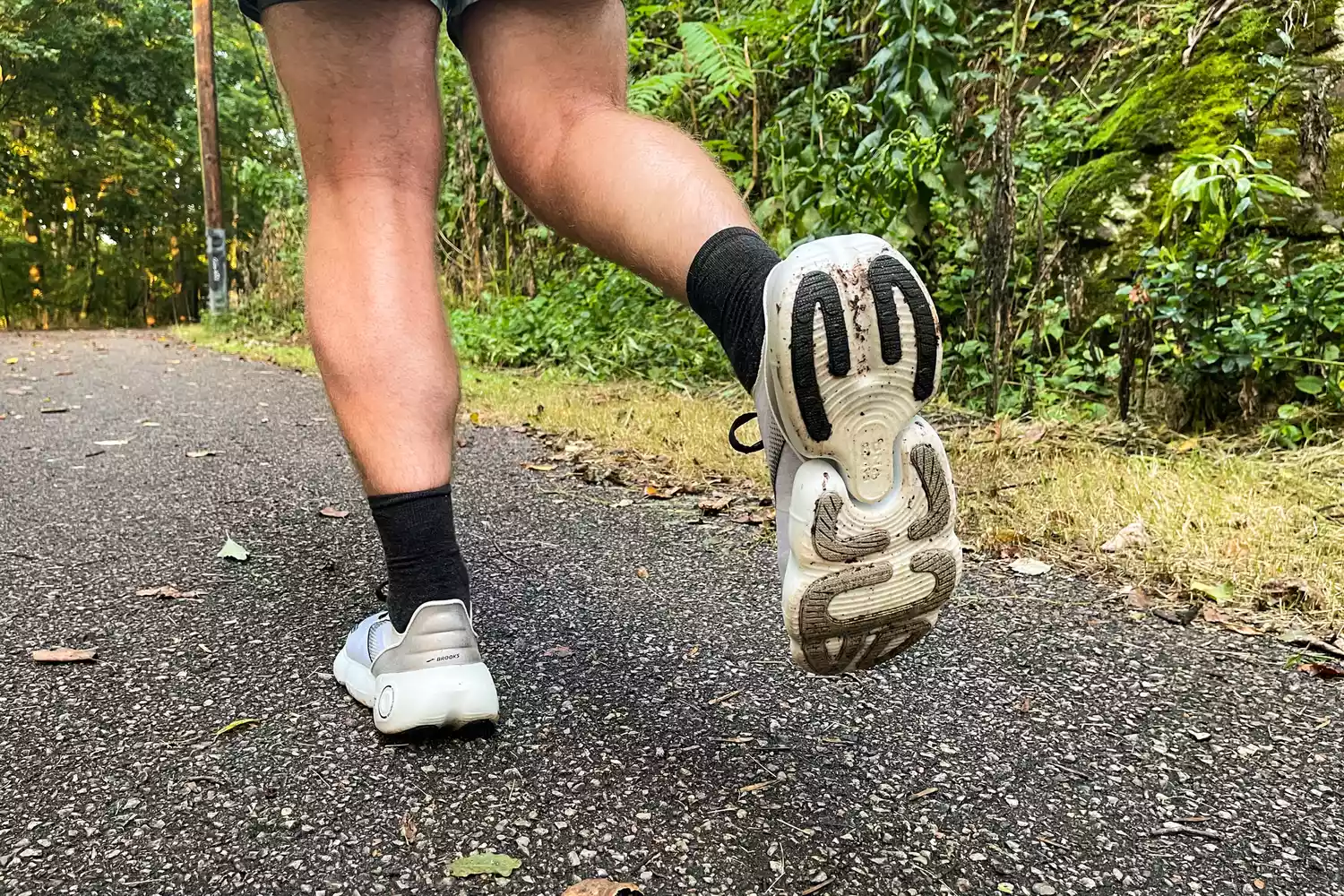 A close-up of a person running while wearing the Brooks Aurora BL sneakers on blacktop