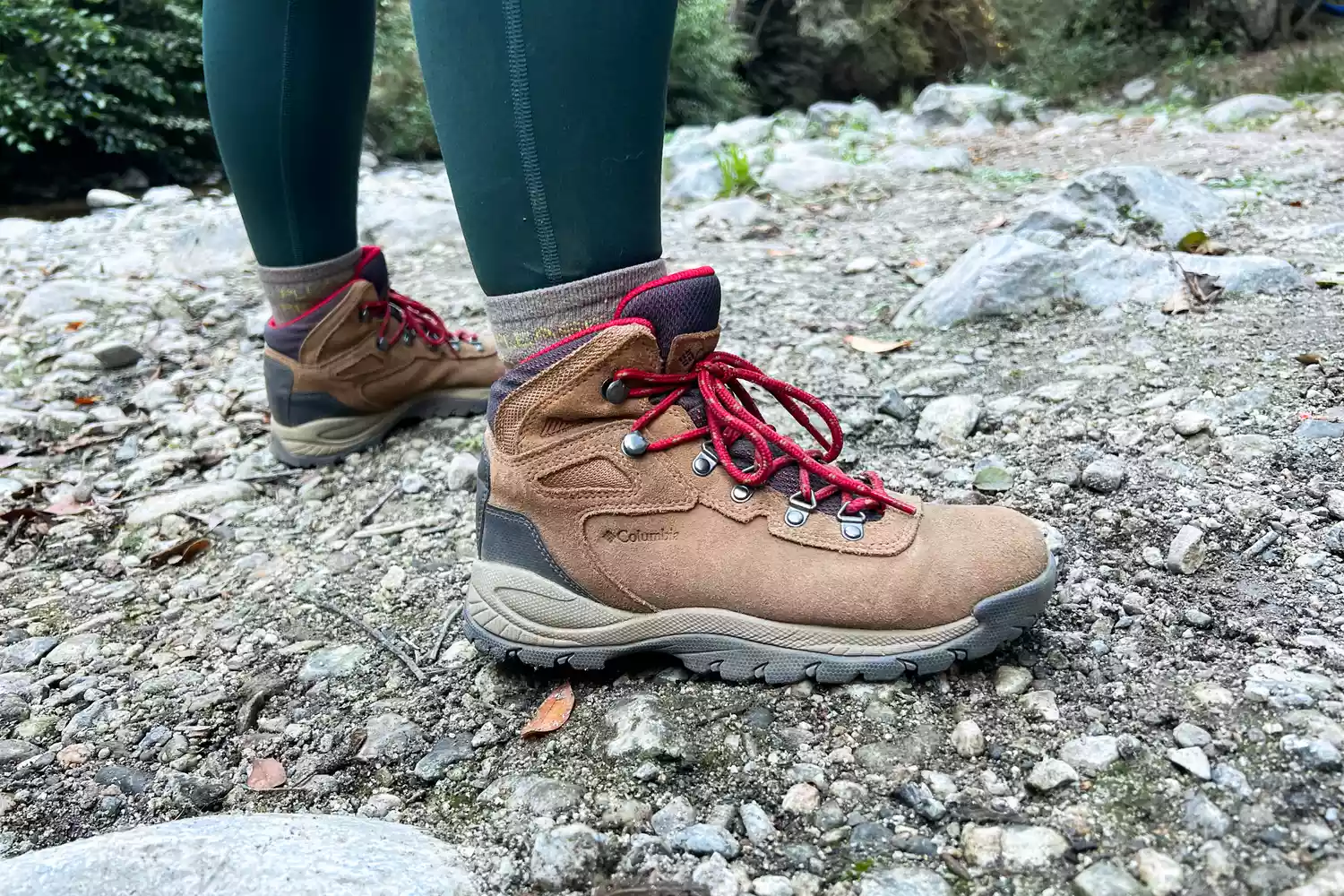 Person wearing Columbia Women’s Newton Ridge Plus Hiking Boots standing on rocky ground