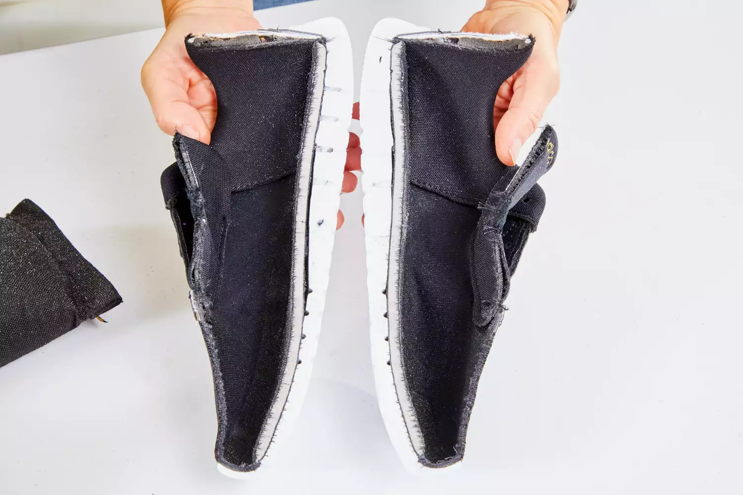 Hands holding Adidas Women's Cloudfoam Qt Racer Running Shoe over a white table