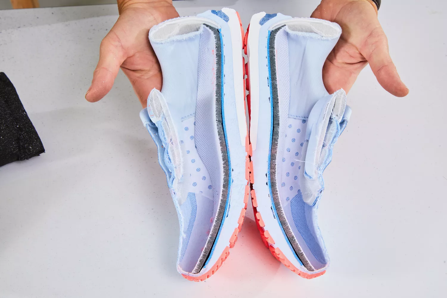 Person holding ASICS Women's GT-2000 10 Running Shoe cut in half