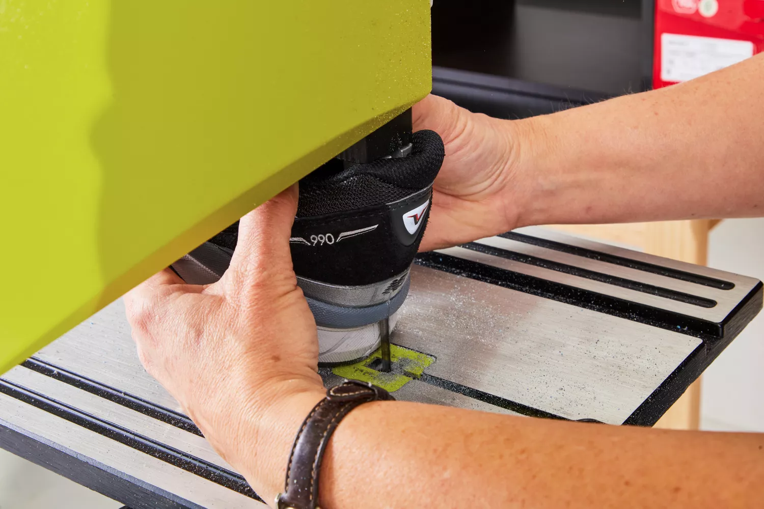 Hands using a saw to cut a New Balance Men's 990v6 Running Shoe in half