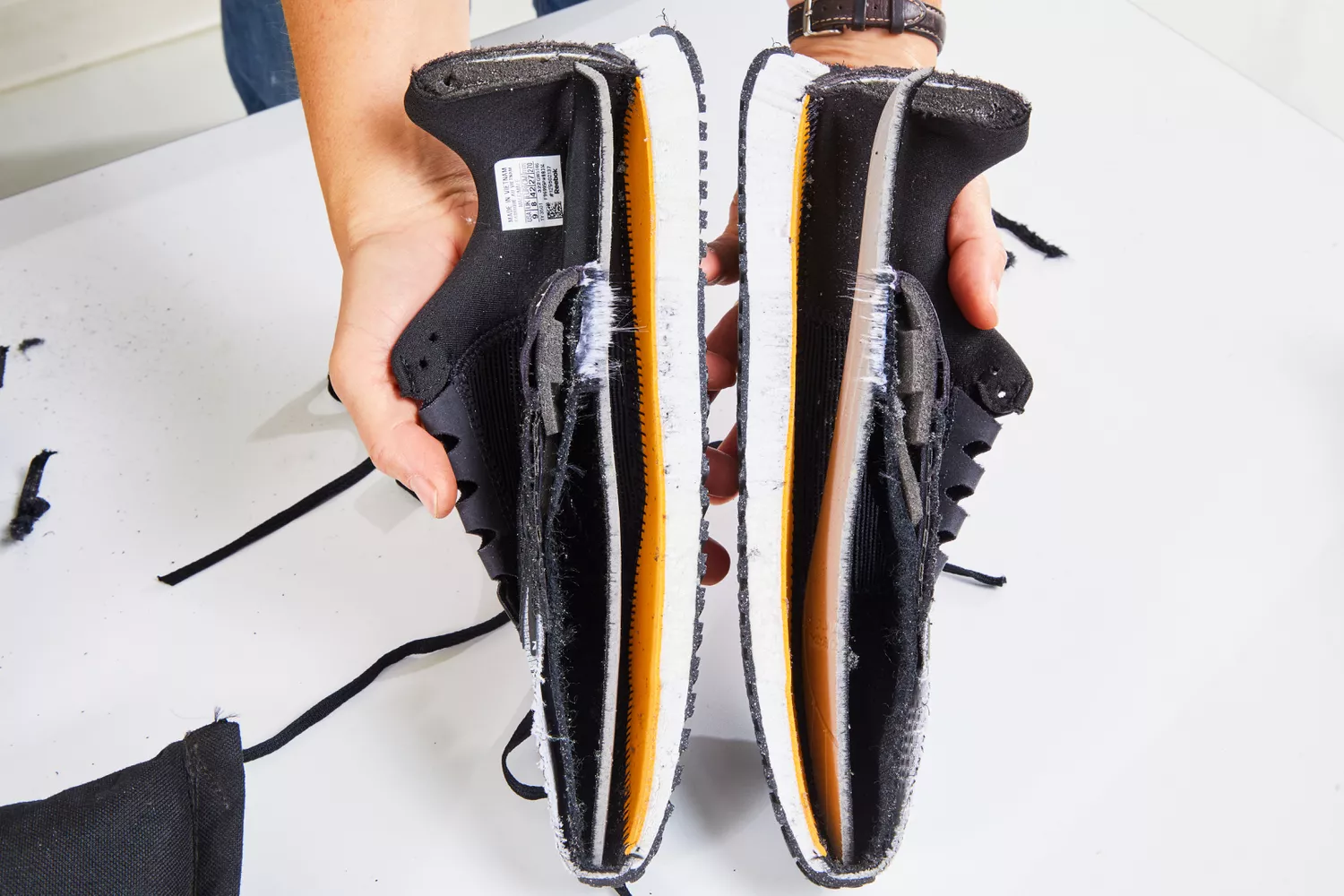 Hands holding a Reebok Men's Nano X2 Cross Trainer that has been cut in half