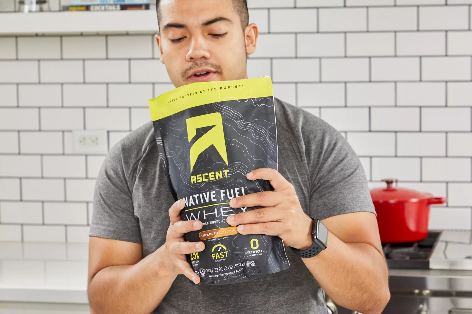 Person holding a package of Ascent Native Fuel Whey Protein Powder