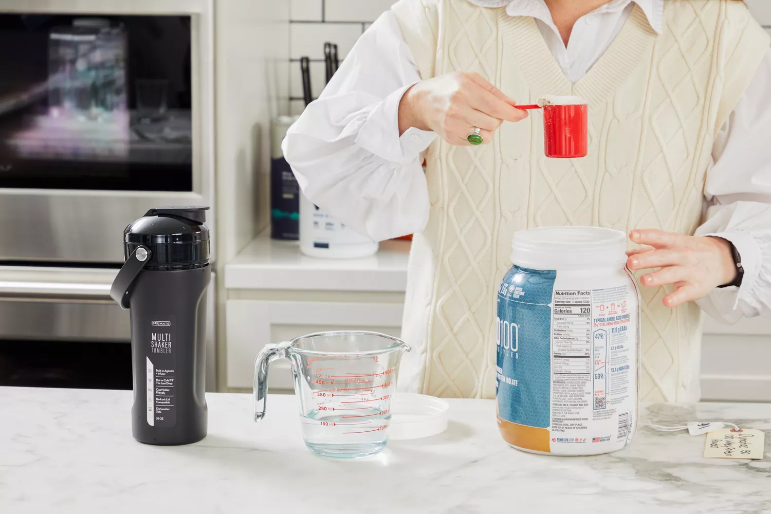 Hand taking a scoop of Dymatize ISO100 Whey Protein Powder Chocolate Peanut Butter out of the jar