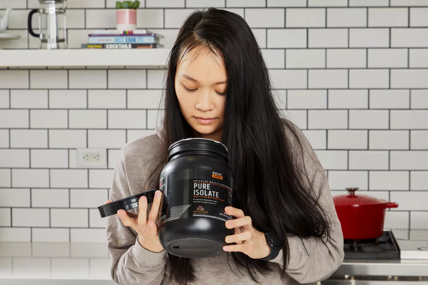 A person looking inside of a jar of GNC AMP Pure Isolate Whey Protein Powder