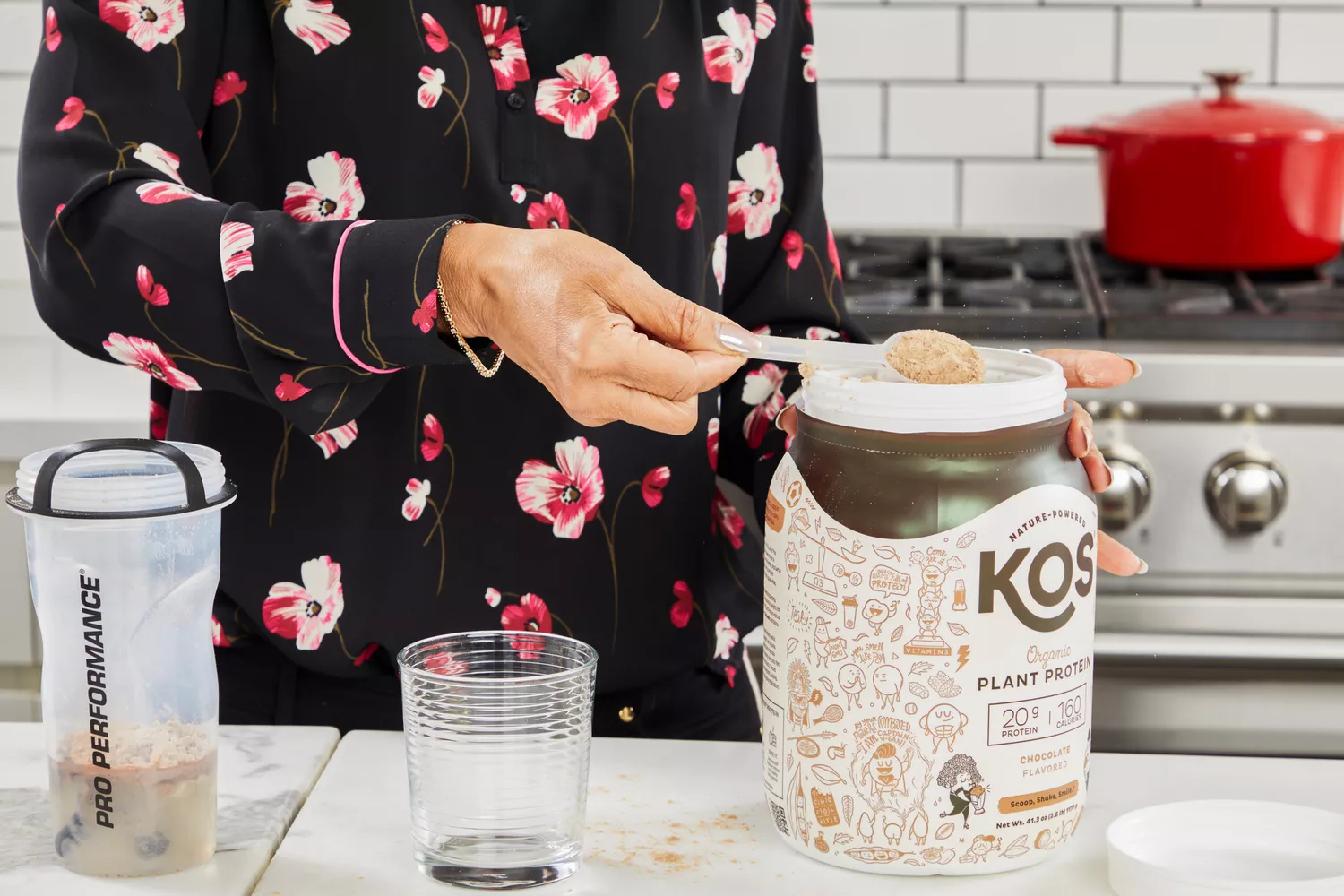 Hand scooping KOS Vegan Superfood Protein Powder from bottle