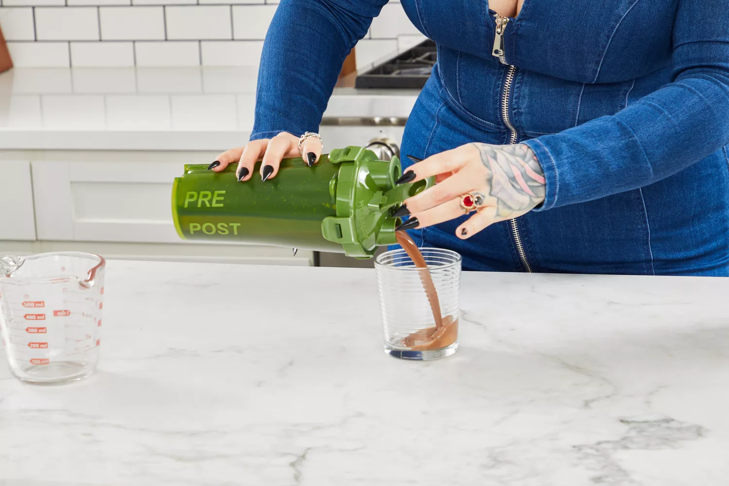 Hands pouring a protein drink from a shaker bottle into a glass