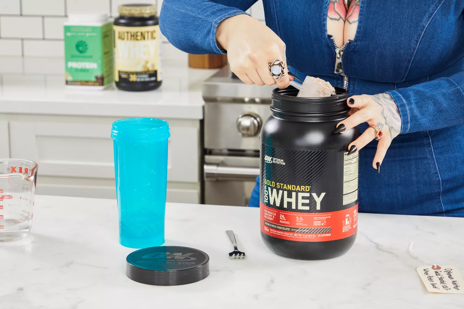 Hand scooping Optimum Nutrition Gold Standard 100% Whey Protein Powder from the jar