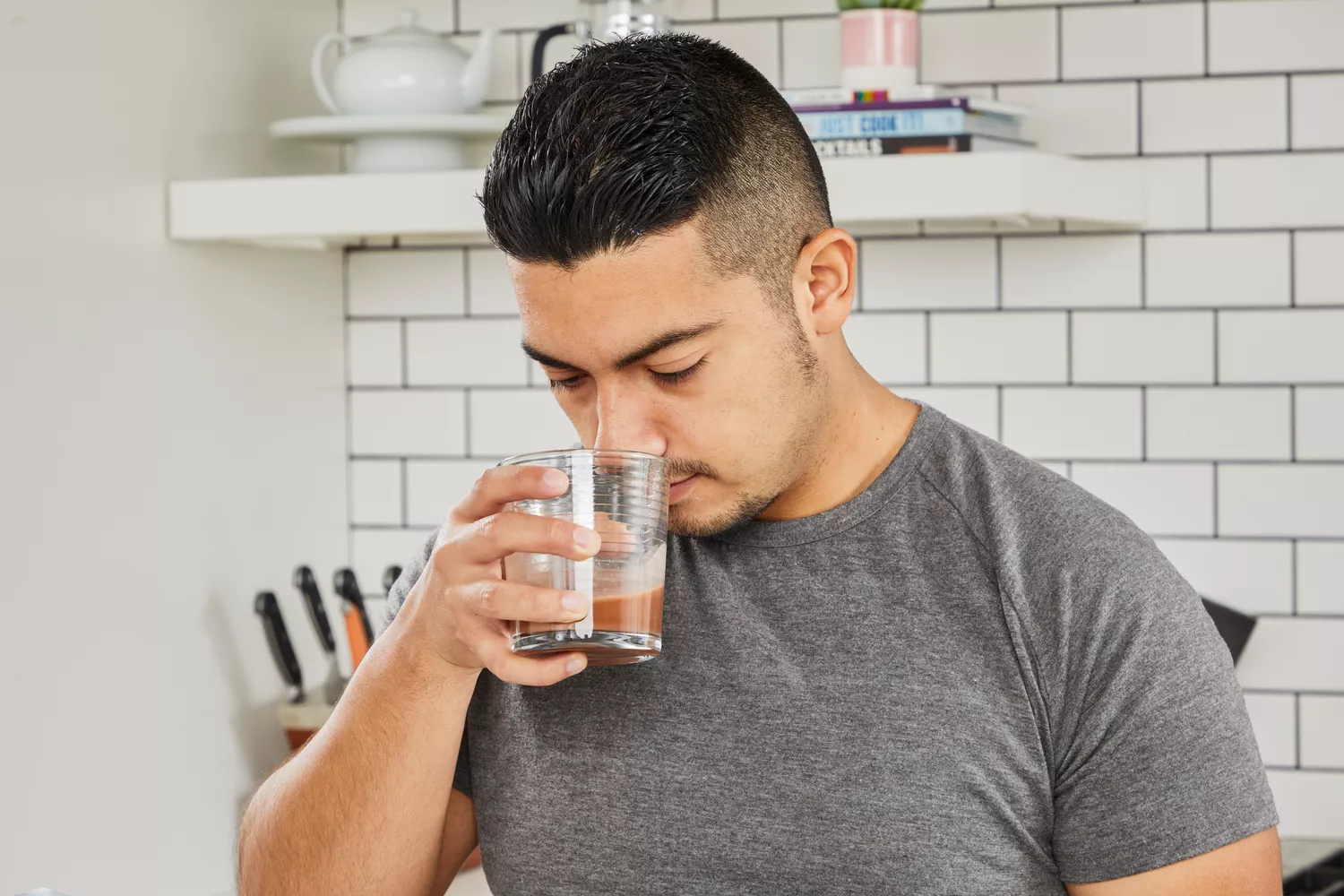 A person sniffing a protein shake in a clear glass
