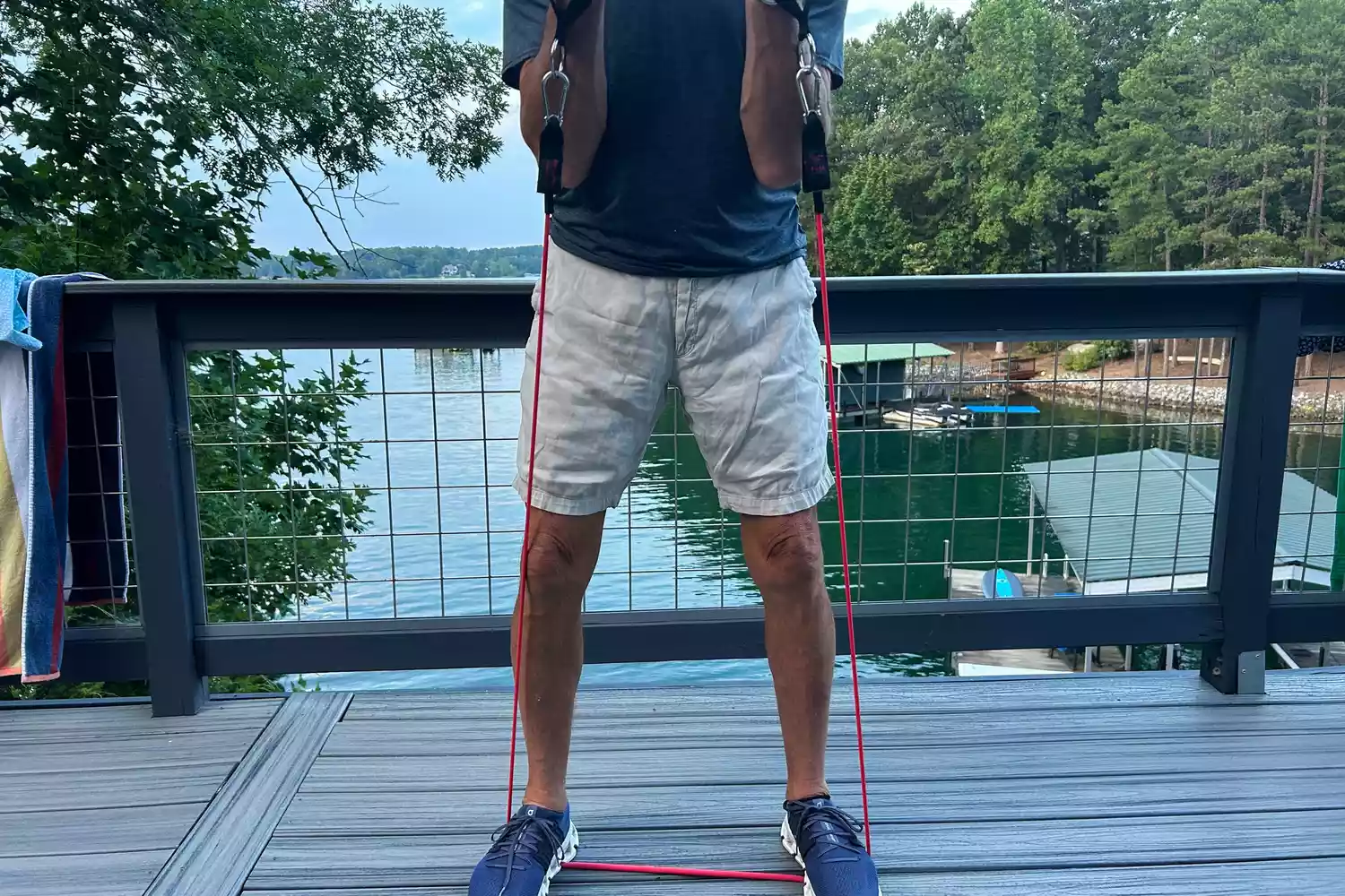 A person doing bicep curl outdoors by using a red band from the Bodylastics Resistance Band Set