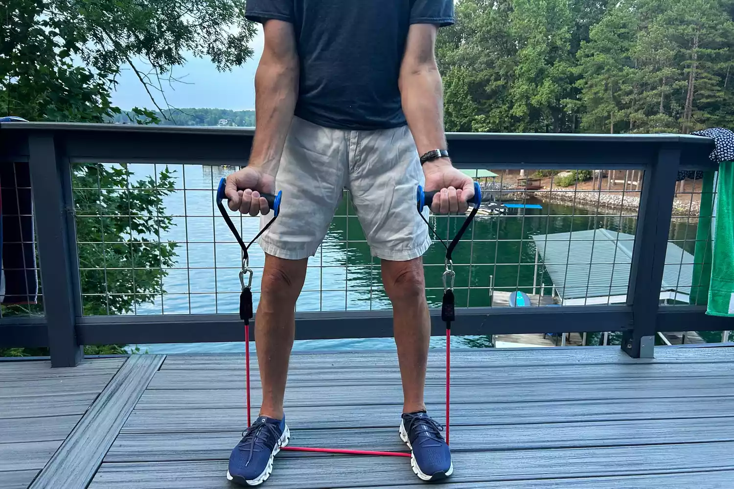 A person standing on a band from the Bodylastics Resistance Band Set while holding onto its handles in an outdoor setting