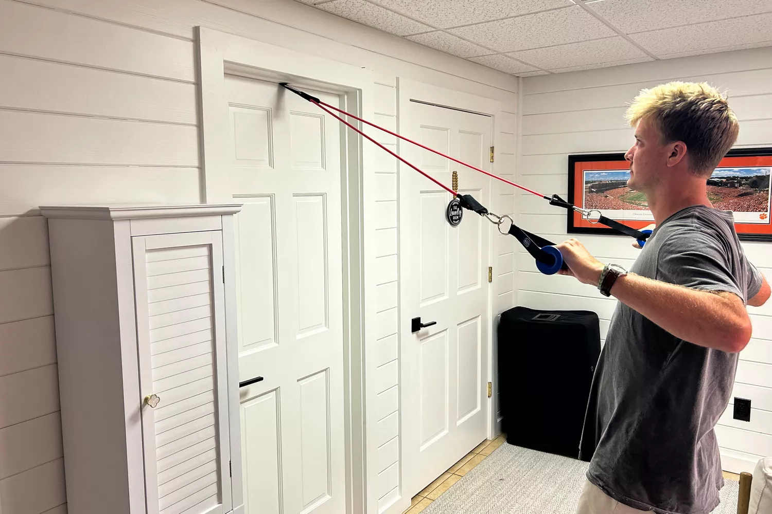 A person using a band from the Bodylastics Resistance Band Set attached to a door