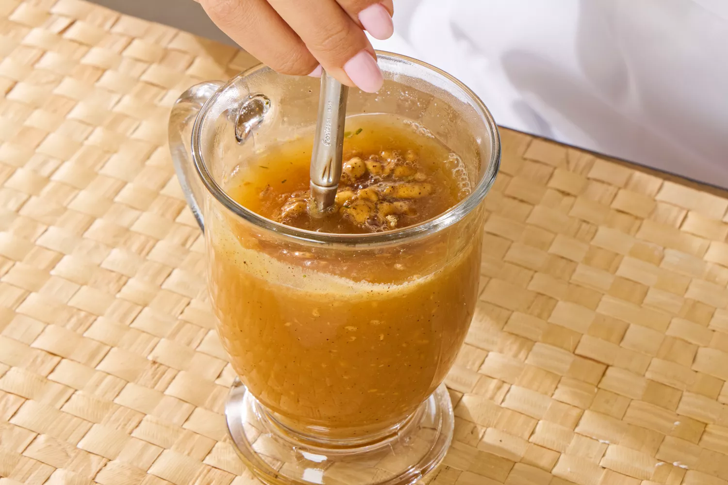 A person stirs the Dr. Kellyann Bone Broth + Digestive Support in a glass