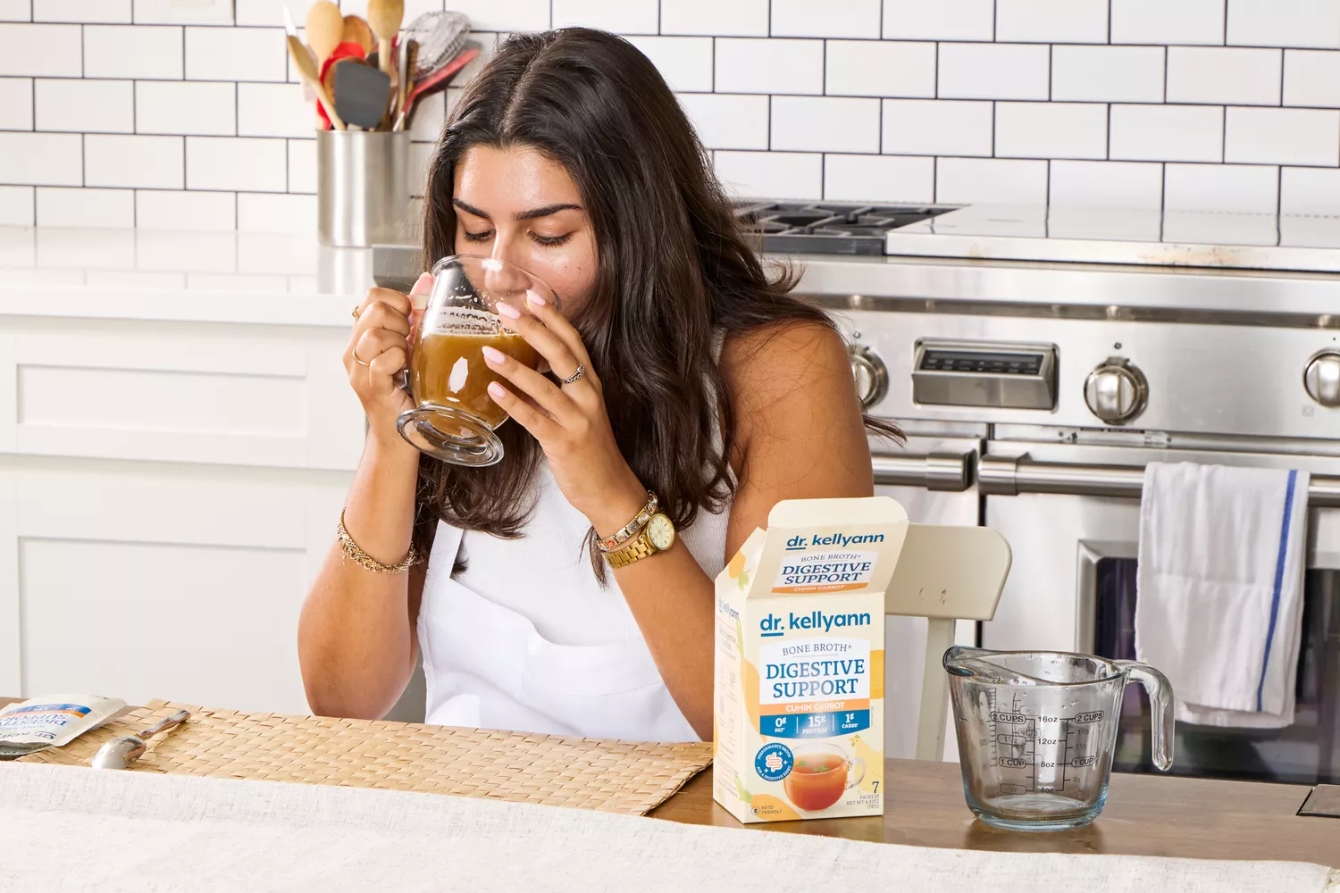 A person drinks a glass of Dr. Kellyann Bone Broth + Digestive Support