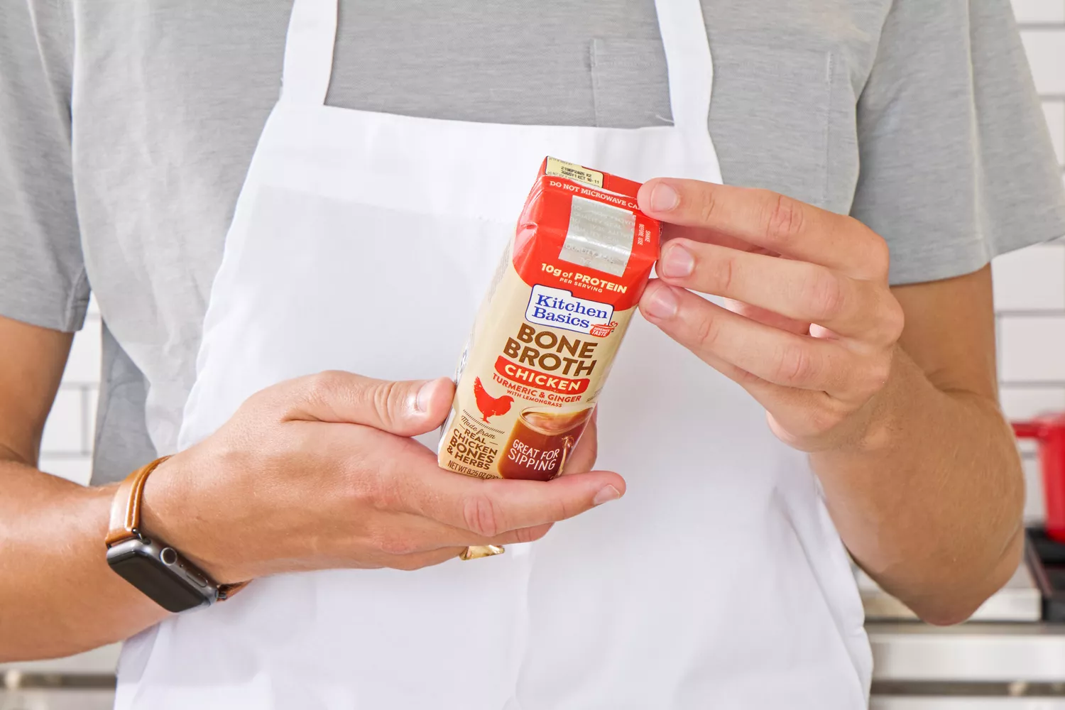 A person reads the back of the Kitchen Basics Turmeric &amp; Ginger With Lemongrass Chicken Bone Broth