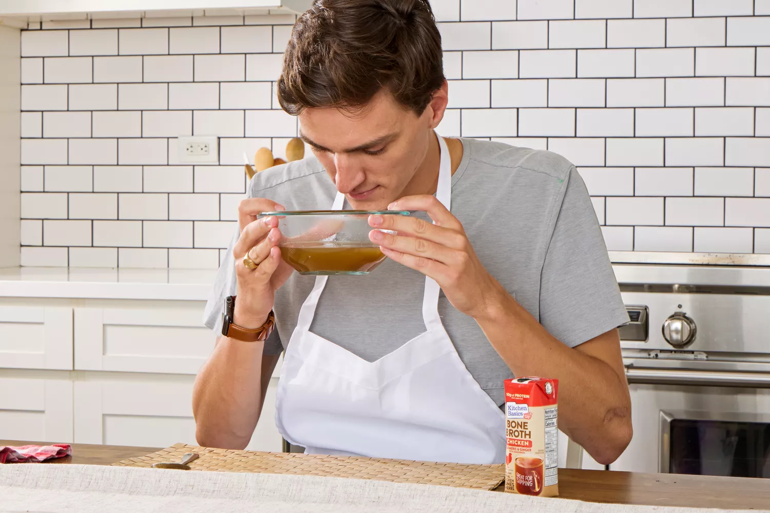 A person smells a bowl of Kitchen Basics Turmeric &amp; Ginger With Lemongrass Chicken Bone Broth