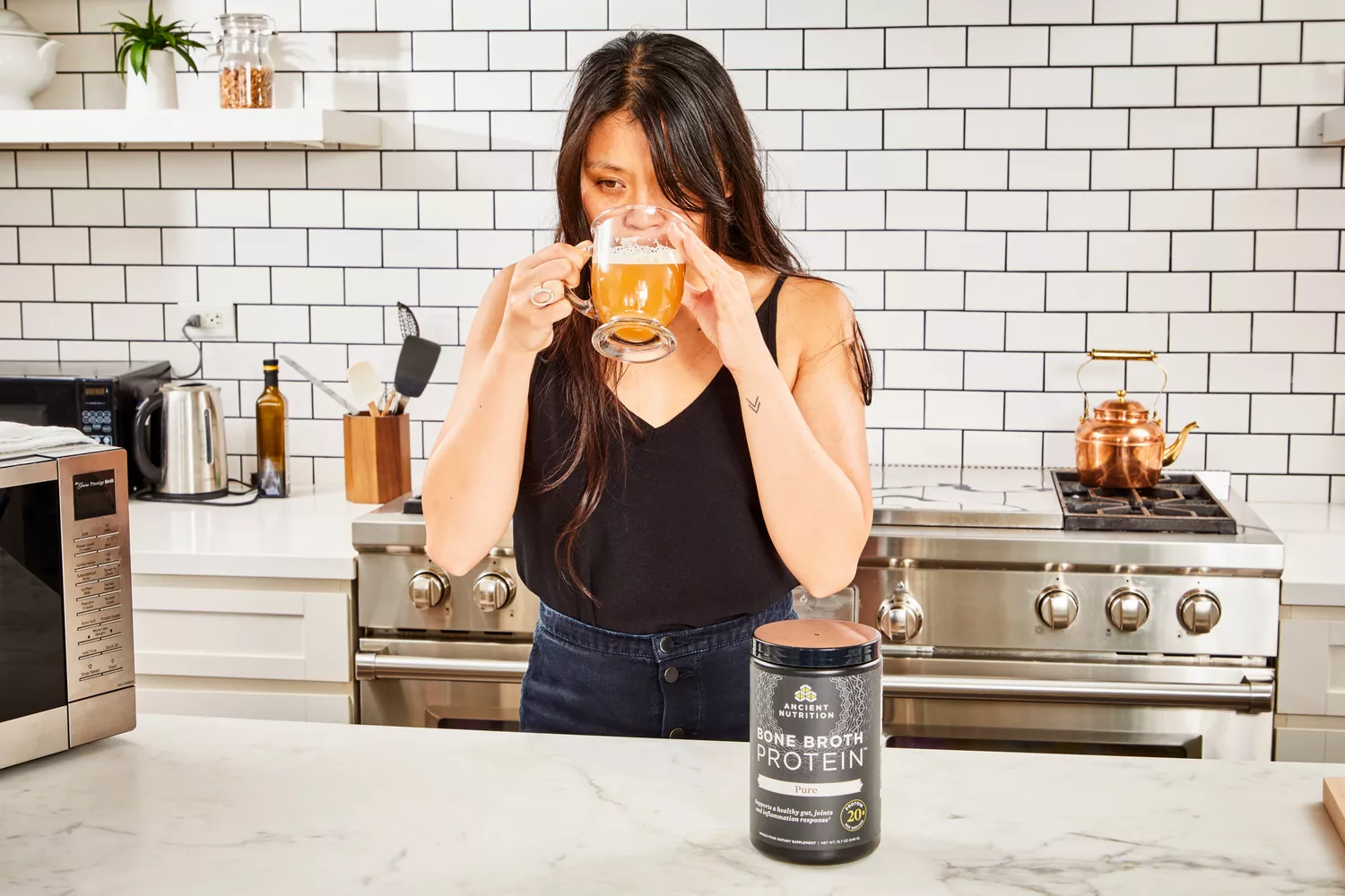 A person drinks a glass of Ancient Nutrition Bone Broth Protein
