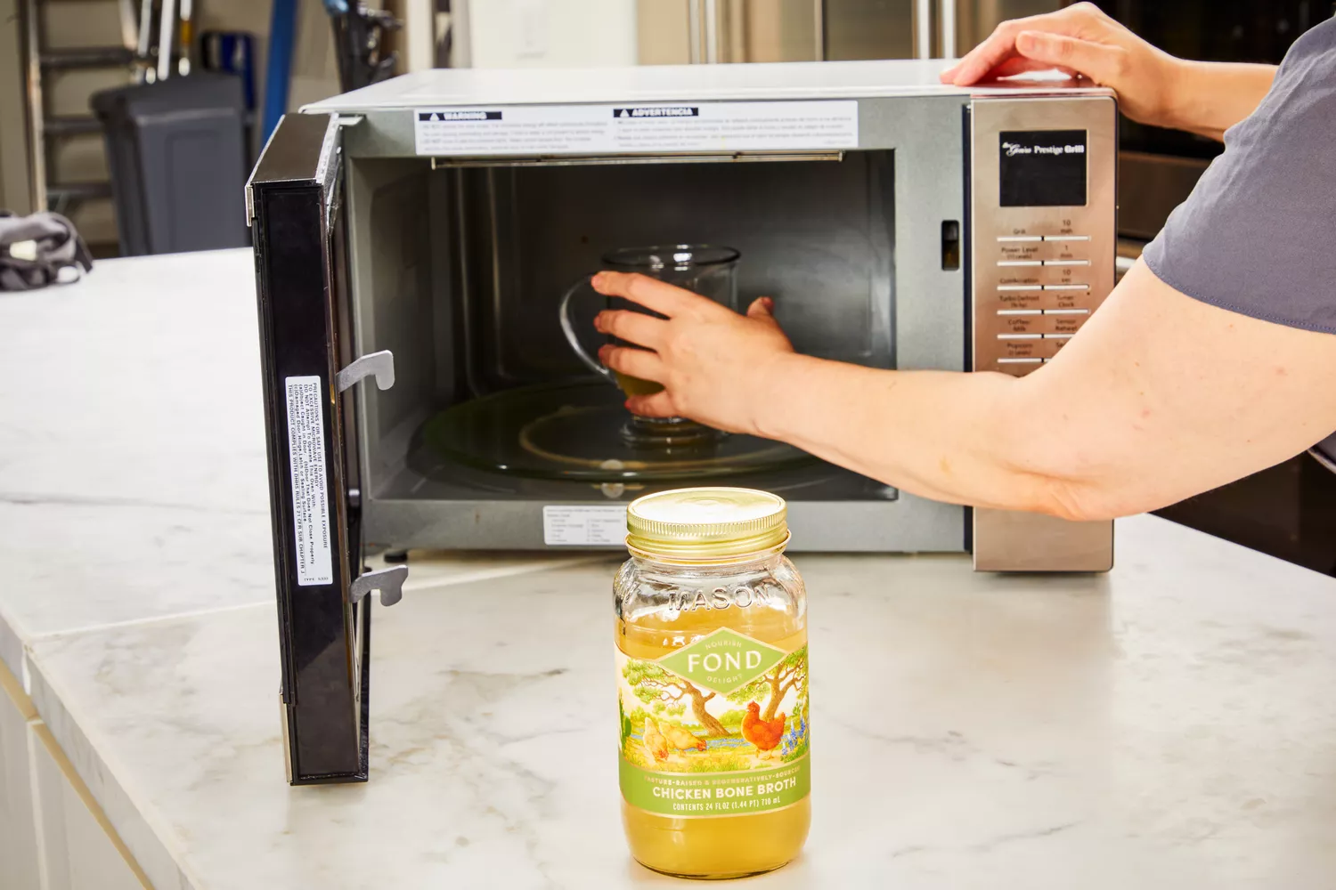A person puts a glass of FOND Certified Organic Chicken Bone Broth in the microwave