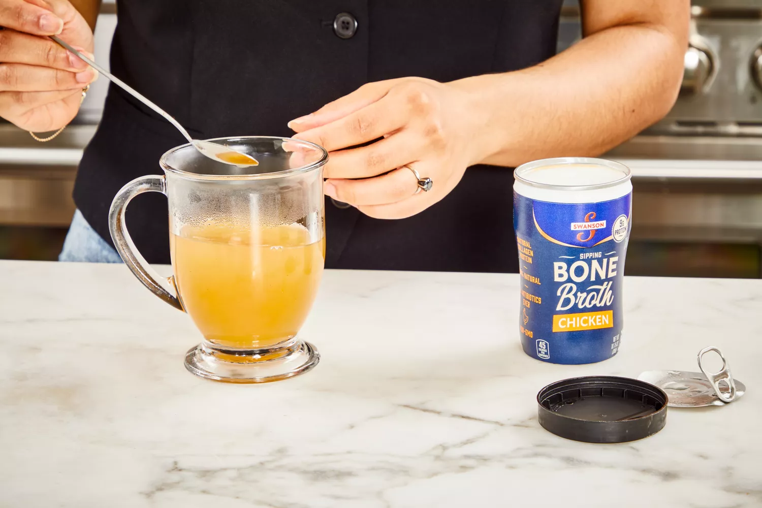 A person stirs Swanson Sipping Chicken Bone Broth powder into water