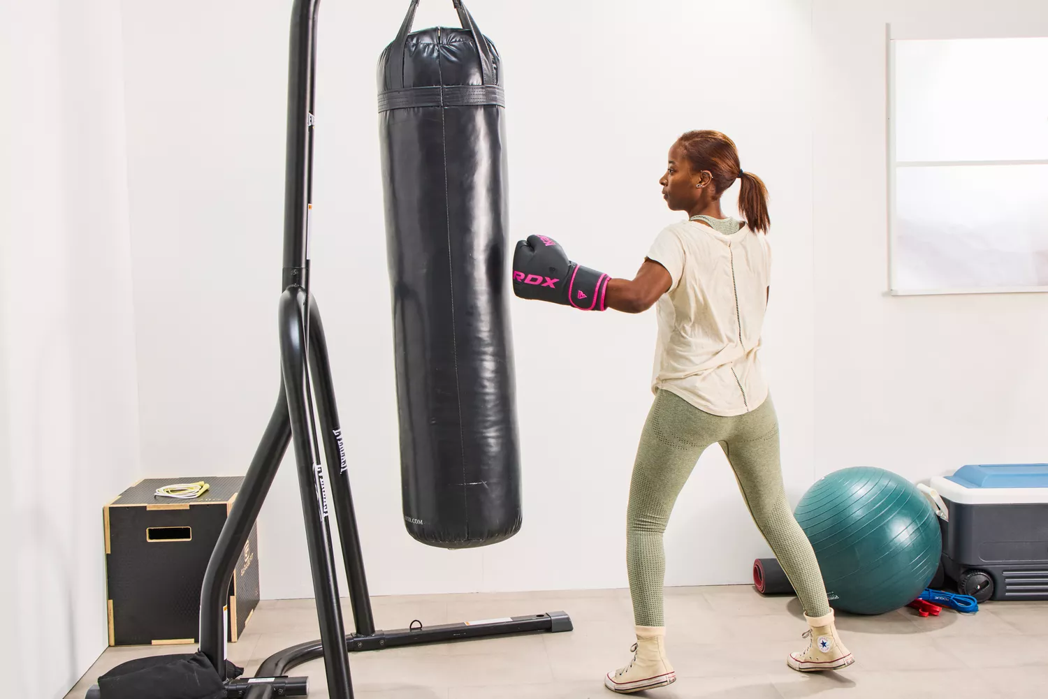 A person punches a bag while wearing the RDX Boxing Gloves