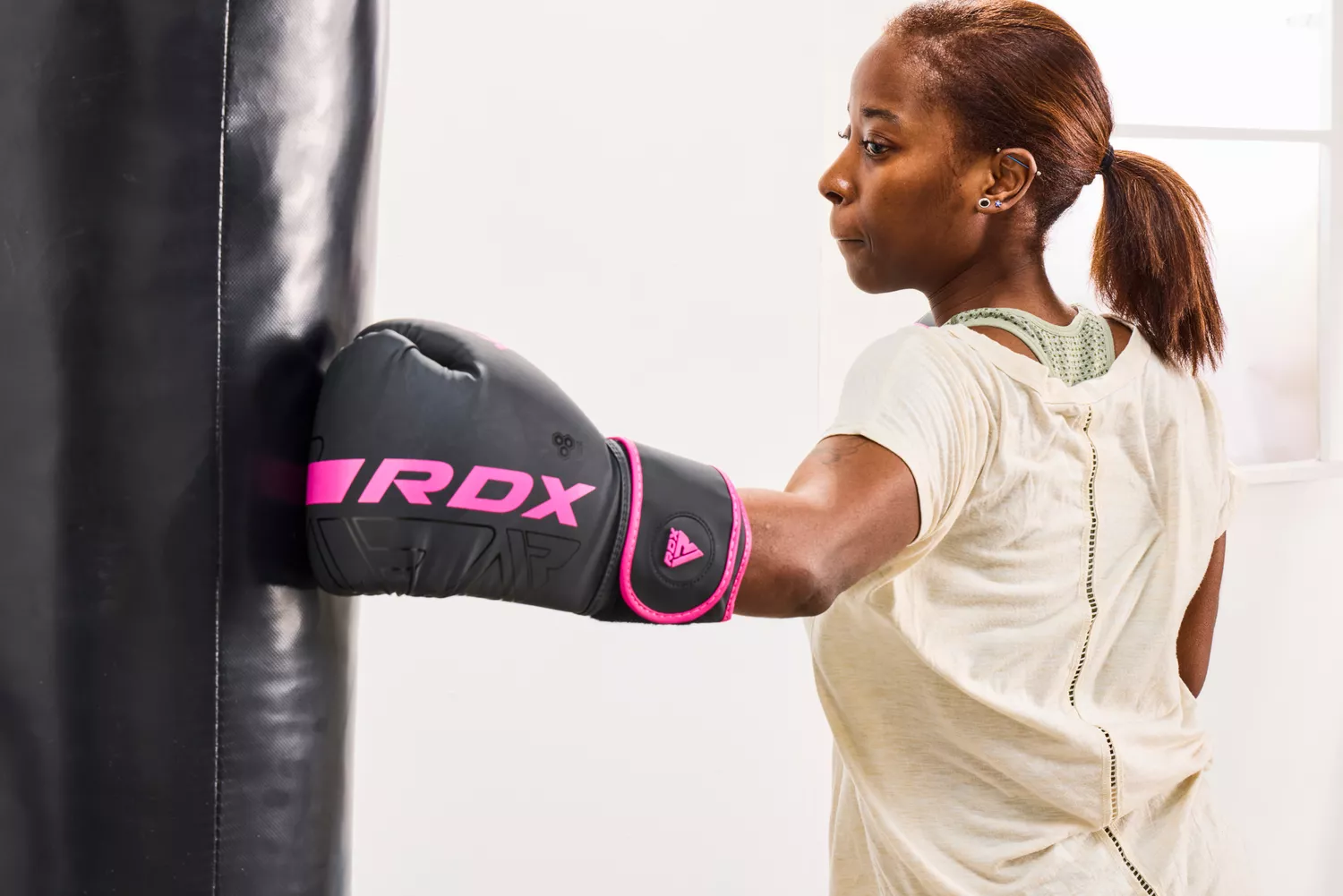 A person punches a bag while wearing the RDX Boxing Gloves