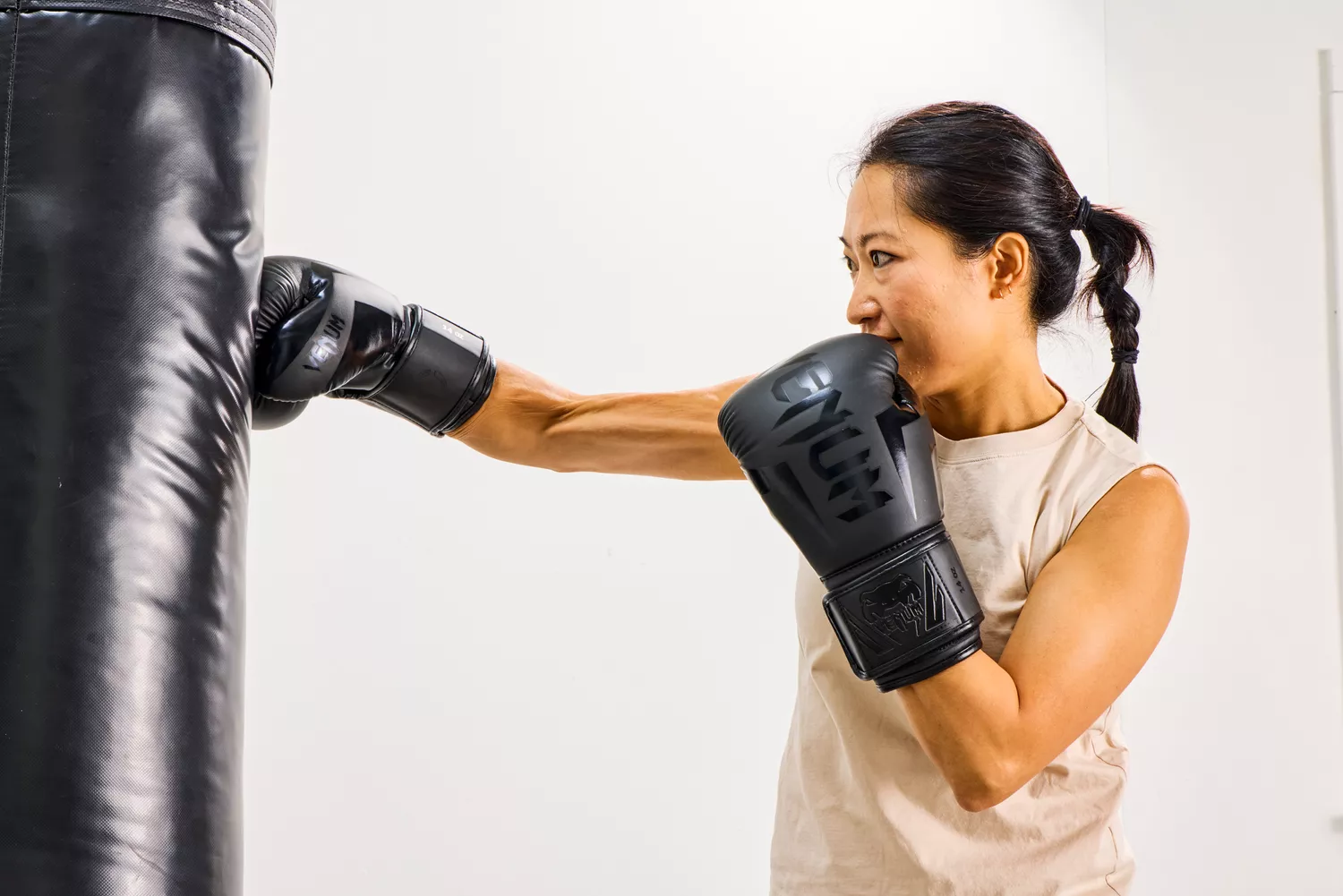 A person punches a bag while wearing the Venum Elite Boxing Gloves