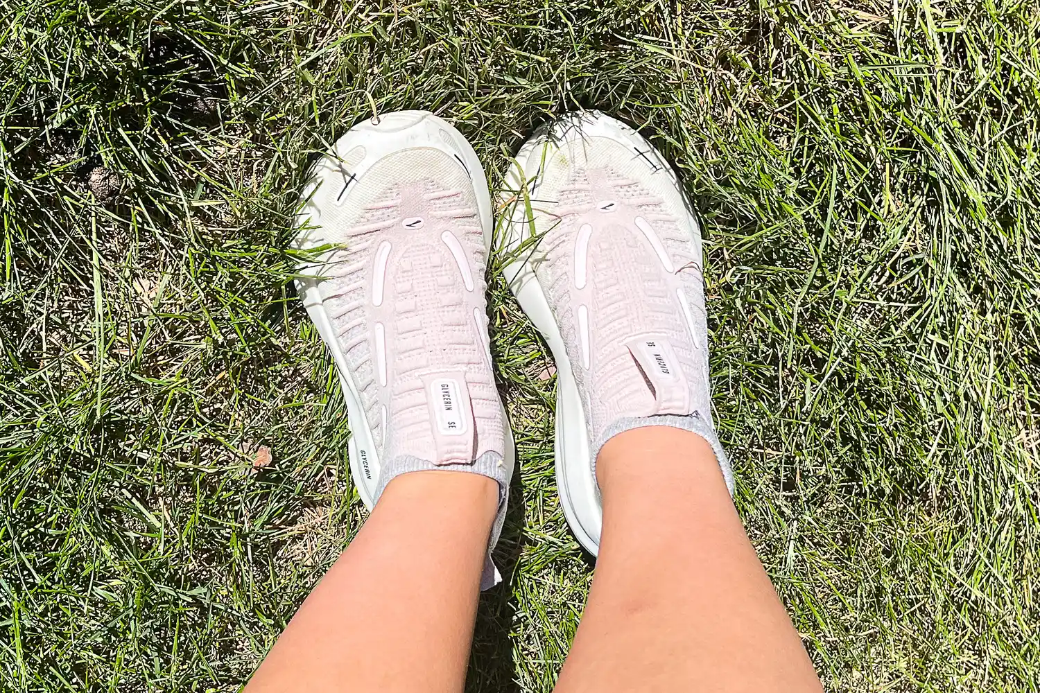 A person stands in grass while wearing the Brooks Women's Glycerin 22 SE Running Shoes