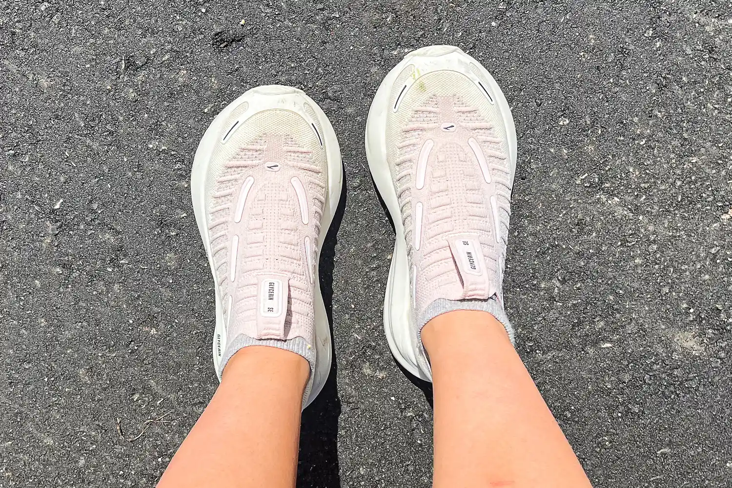 A person walks on asphalt while wearing the Brooks Women's Glycerin 22 SE Running Shoes