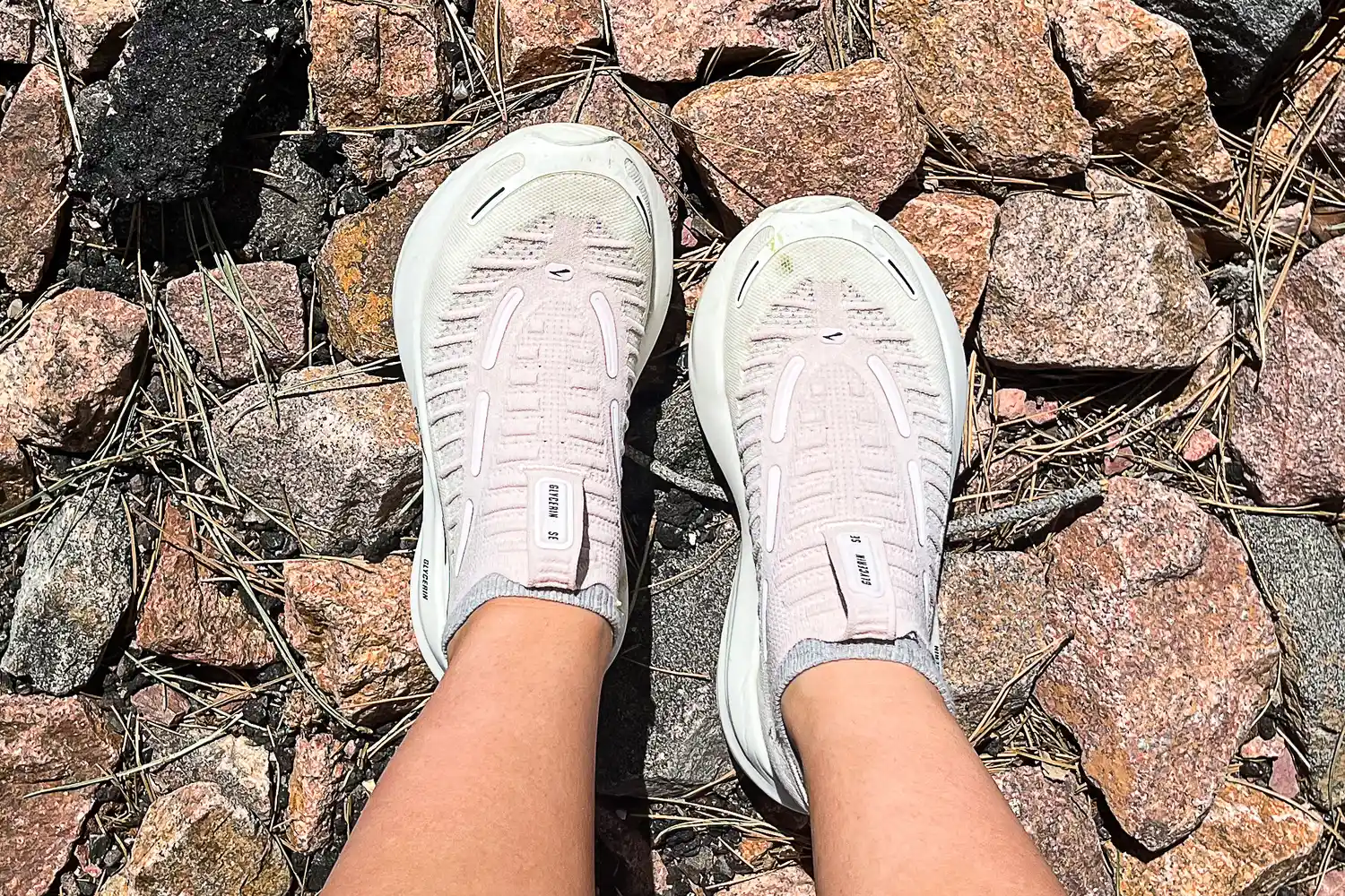 A person wears the Brooks Women's Glycerin 22 SE Running Shoes while standing on rocky ground