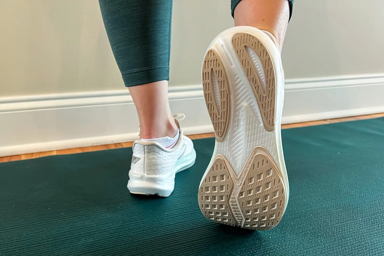 Close-up of a person wearing athletic shoes stepping onto a yoga mat