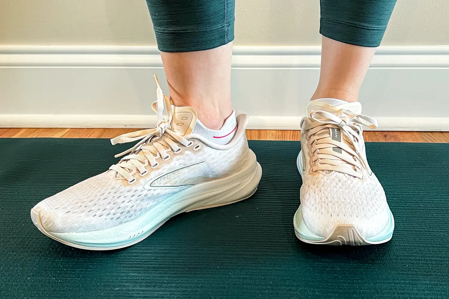 A pair of athletic shoes on feet, shown indoors on a mat