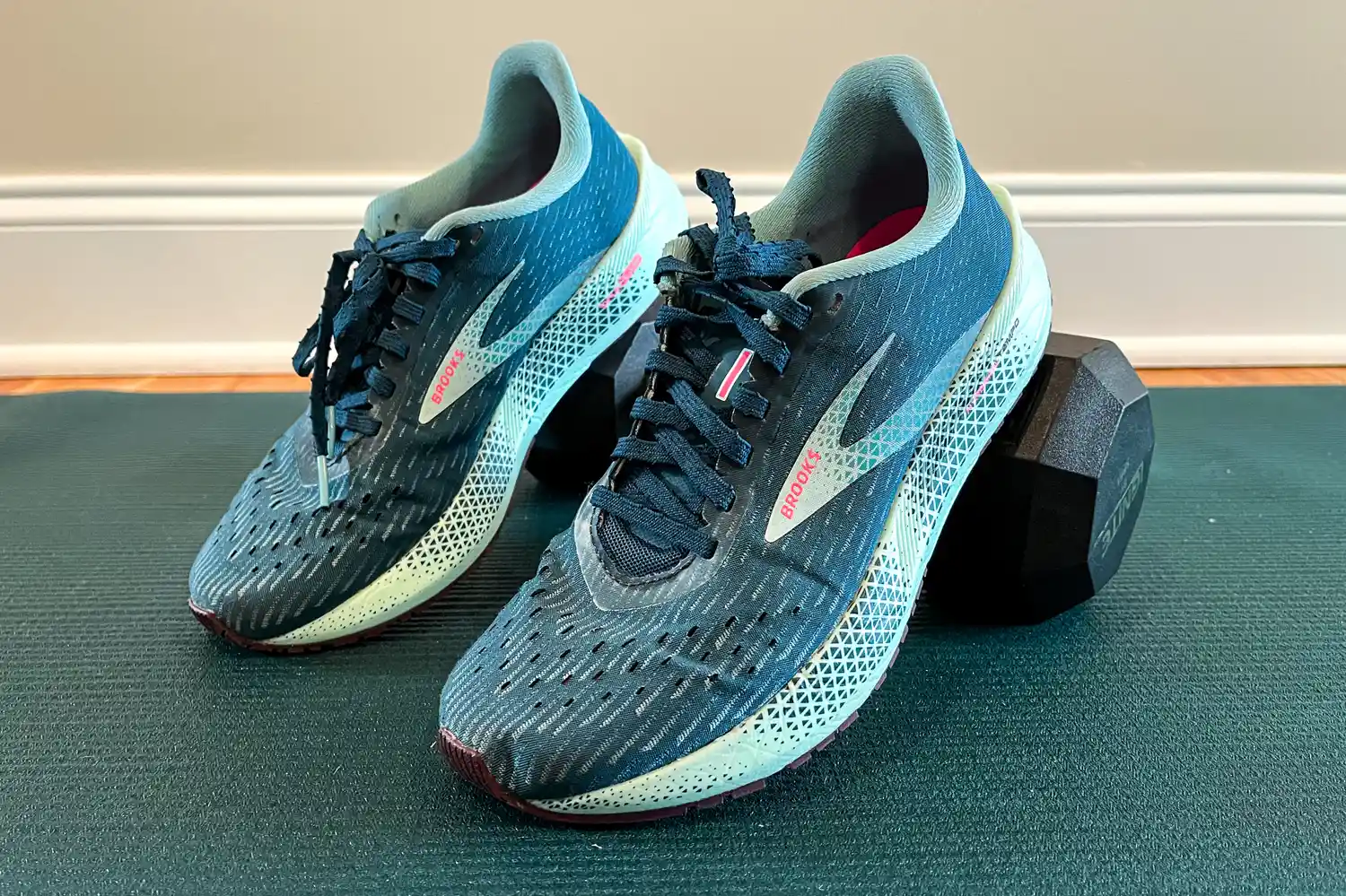 Pair of Brooks running shoes placed on a dumbbell and exercise mat