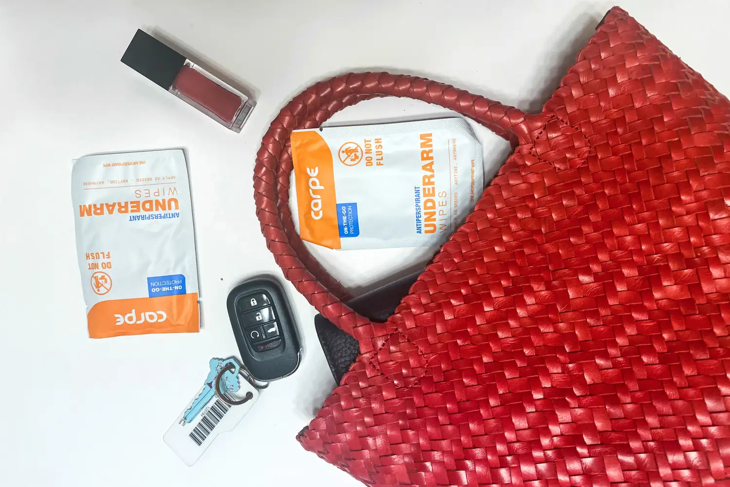 The Carpe On-the-Go Antiperspirant Underarm Wipes spill from a red purse