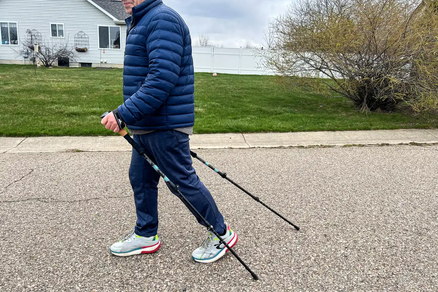 A person uses the Cascade Mountain Aluminum Quick Lock Trekking Poles with Cork Grip while walking