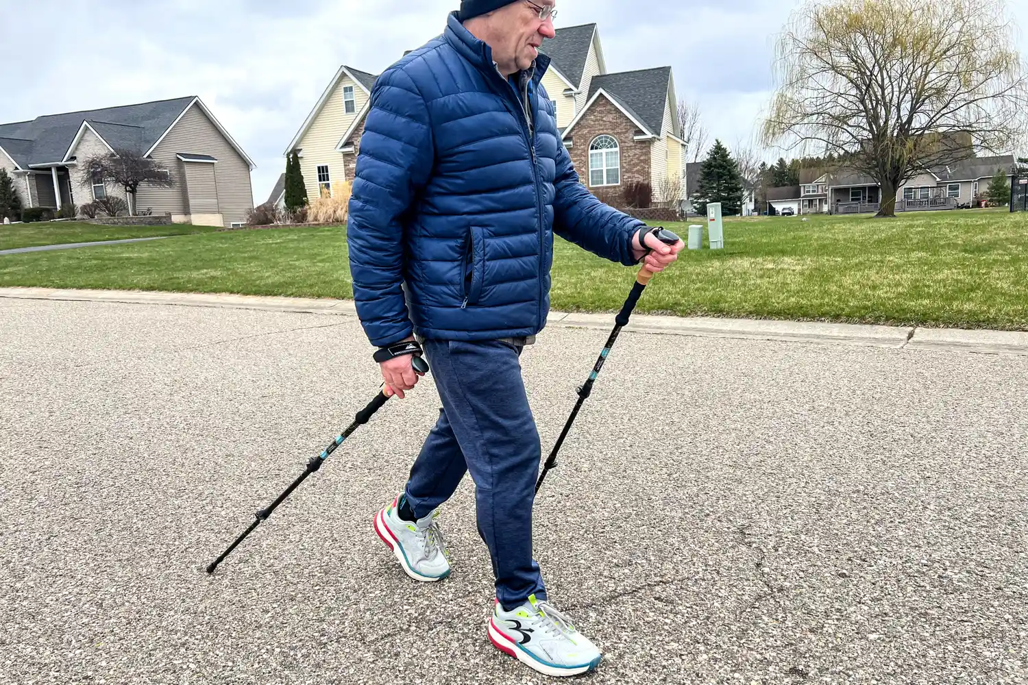 A person walks down a street while using the Cascade Mountain Aluminum Quick Lock Trekking Poles with Cork Grip