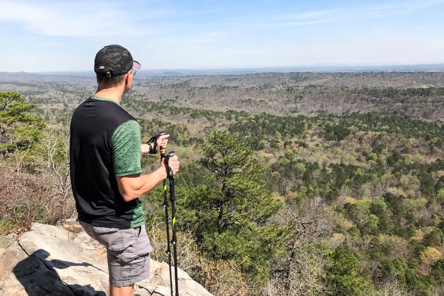 A person stands on a rock while using the Cascade Mountain Tech Carbon Fiber Quick Lock Trekking Poles