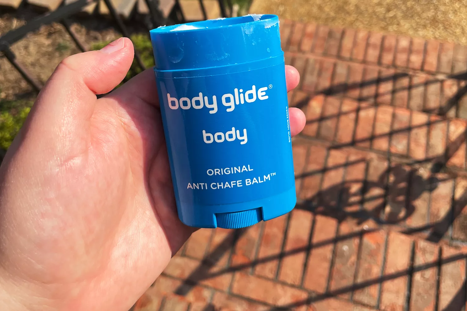 A person holds up a stick of BodyGlide Original Anti-Chafe Balm