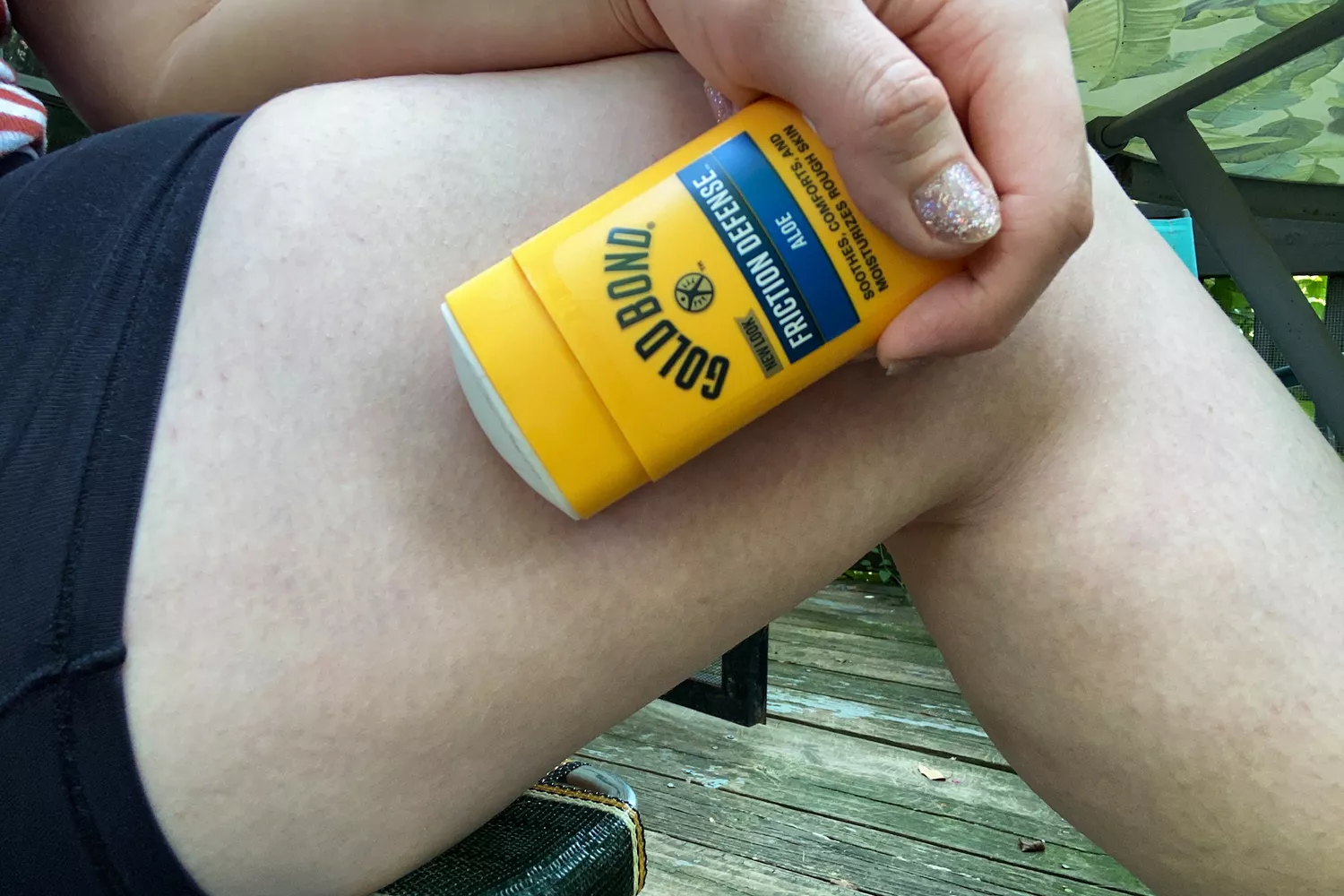 A person applies Gold Bond Friction Defense Moisturizing Stick to their inner thigh