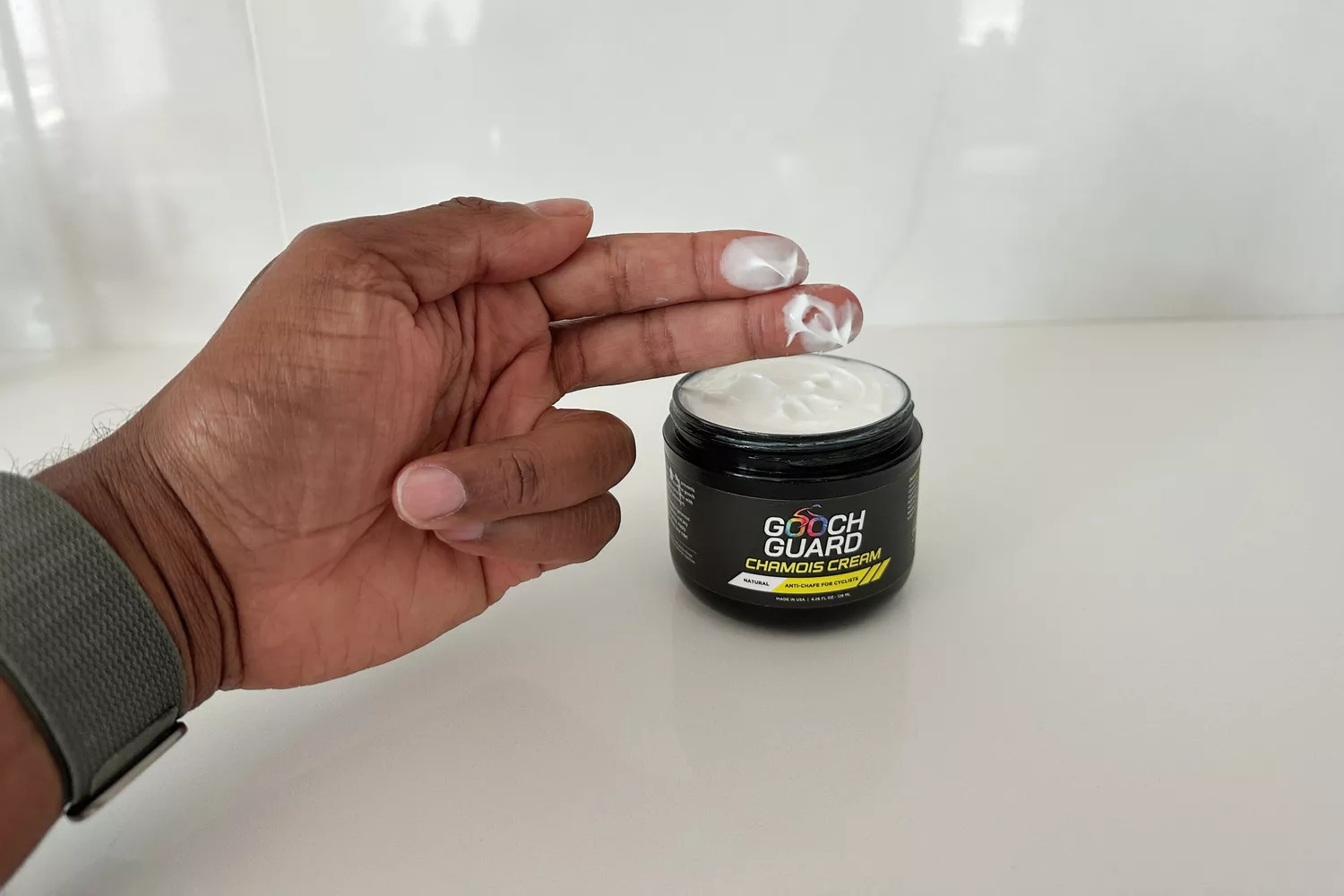 A person removes some Gooch Guard Chamois Cream with their fingers