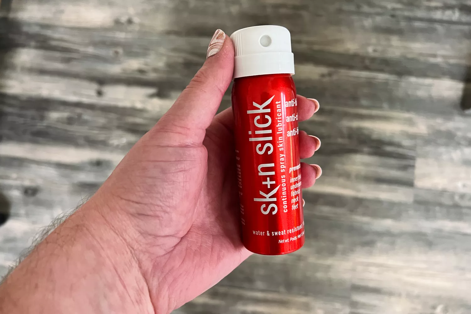 A person holds a can of SBR Skin Slick All Sport Anti-Chafe Spray