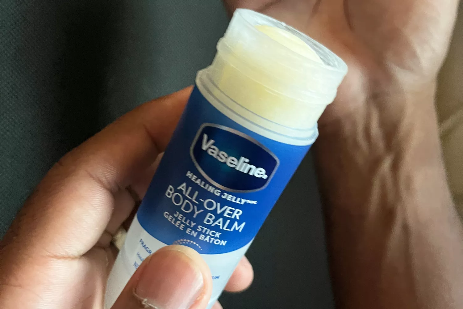 A person holds the Vaseline All-Over Body Balm Stick