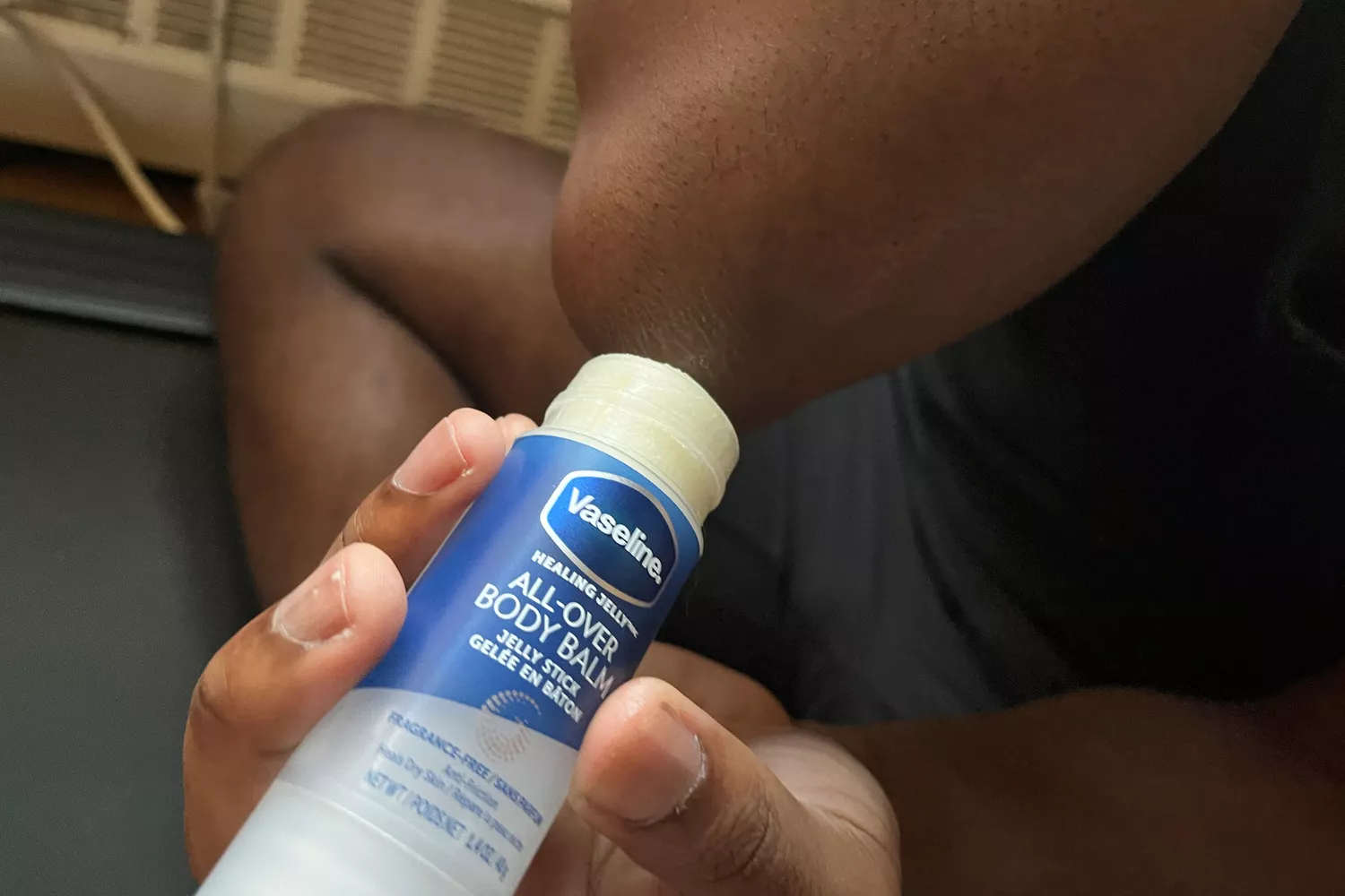 A person applies Vaseline All-Over Body Balm Stick to their elbows