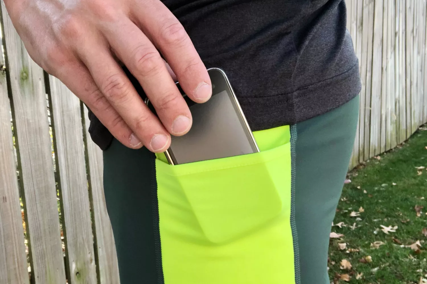 Person putting a phone in the side pocket on a Brooks Men's Run Visible Thermal Tight