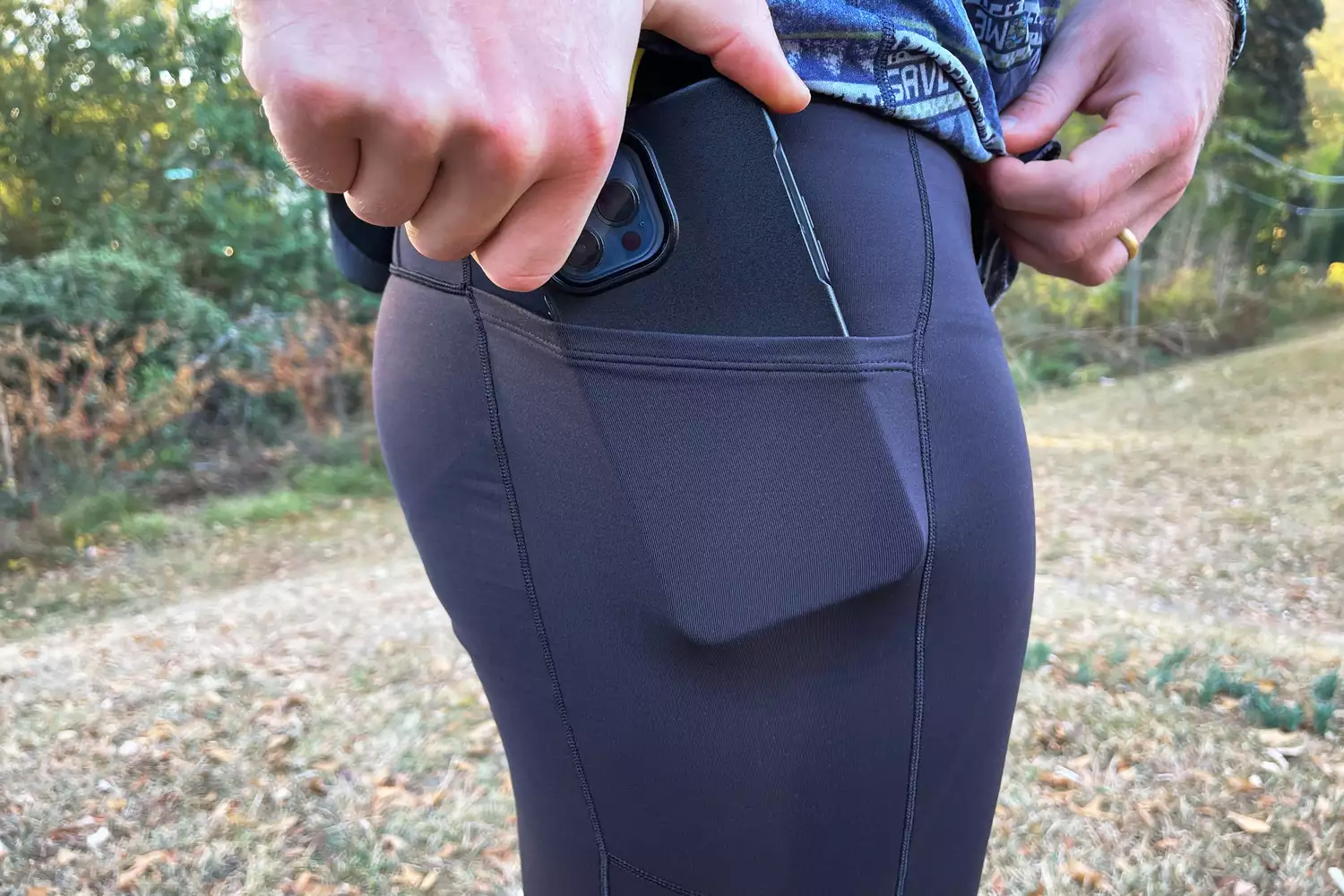 Person putting a phone in the pocket of a Patagonia Men's Peak Mission 28 Inch Tights